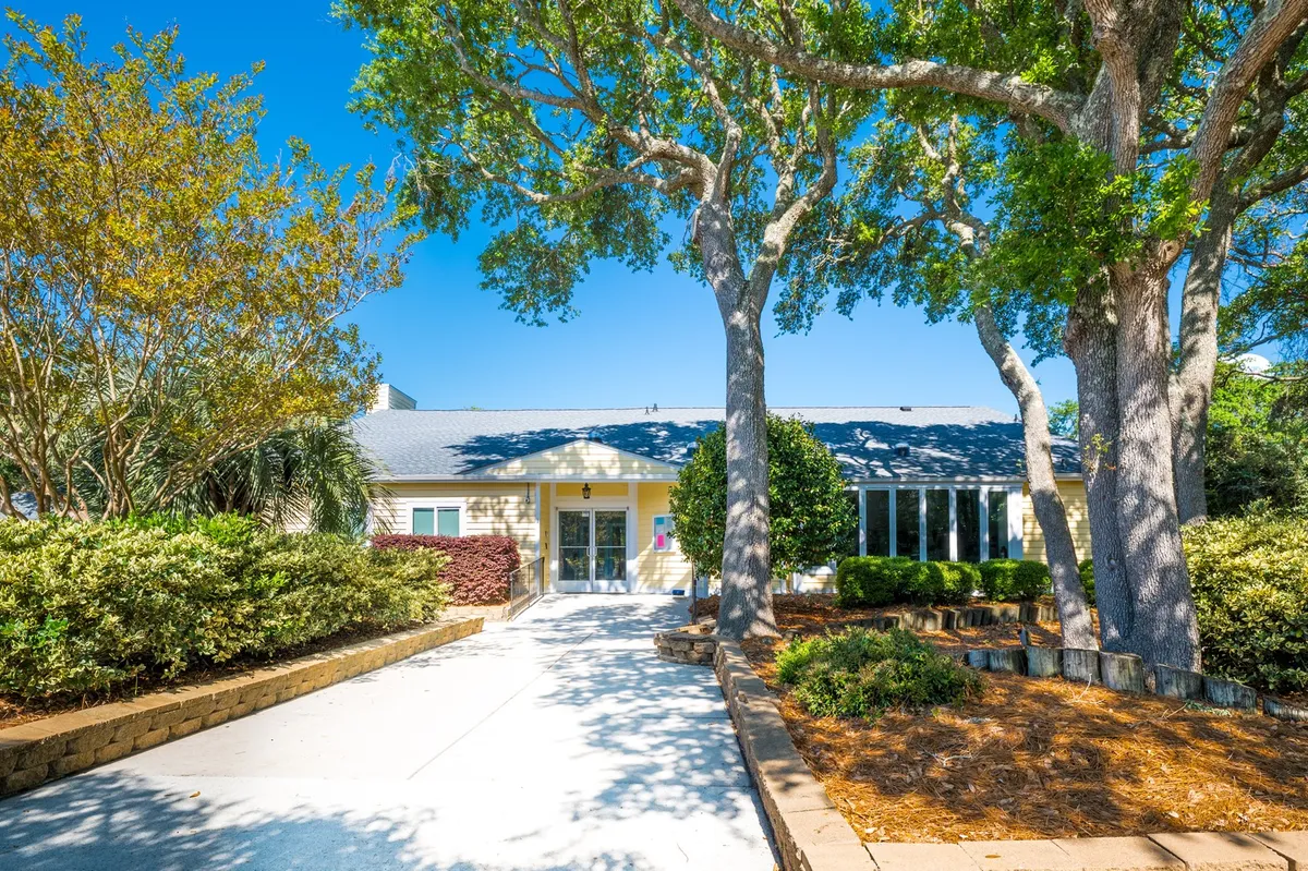 The front entrance of the property surrounded by mature trees and a landscaped garden. The image feels welcoming and showcases a space that can host family gatherings or quiet relaxation outdoors, hinting at the ease of arrival and the property's inviting communal atmosphere.