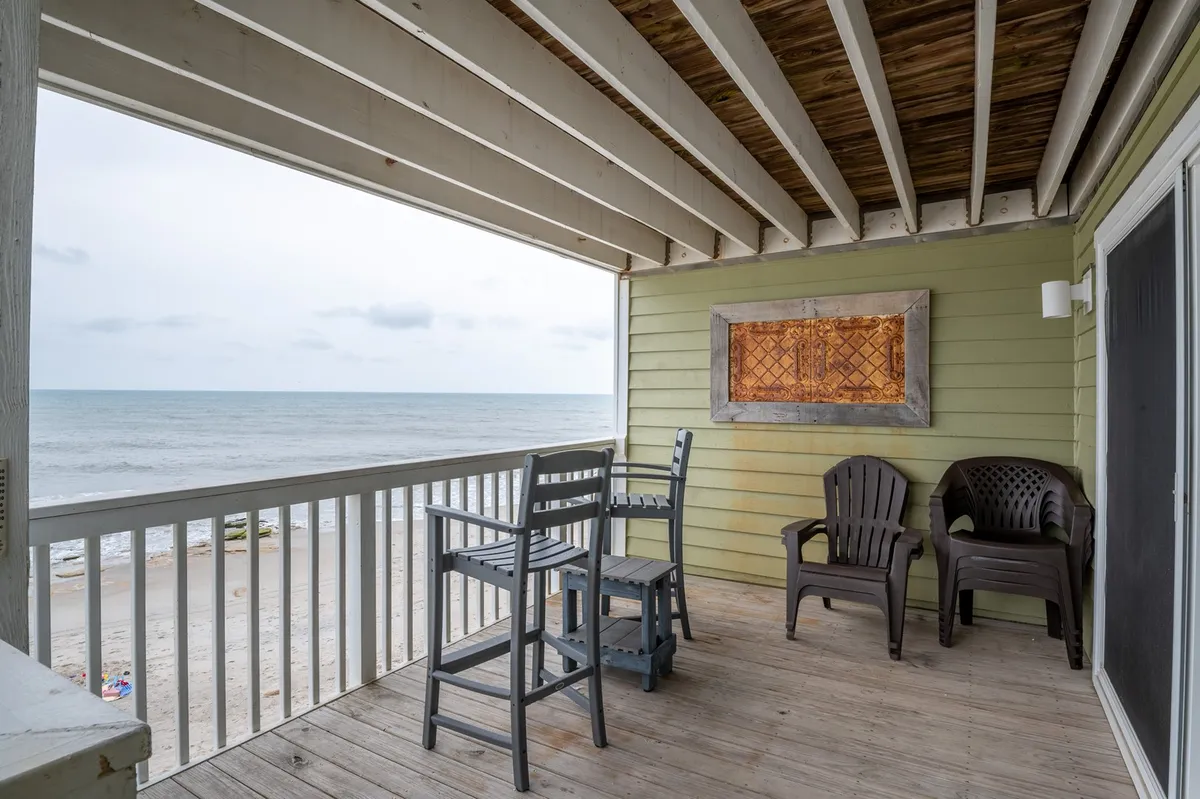 A serene exterior scene featuring a patio with comfortable outdoor furniture, overlooking the sea. The setting includes a decorative wall panel, evoking a sense of tranquility and providing a perfect spot for enjoying the view, morning coffee, or evening drinks.