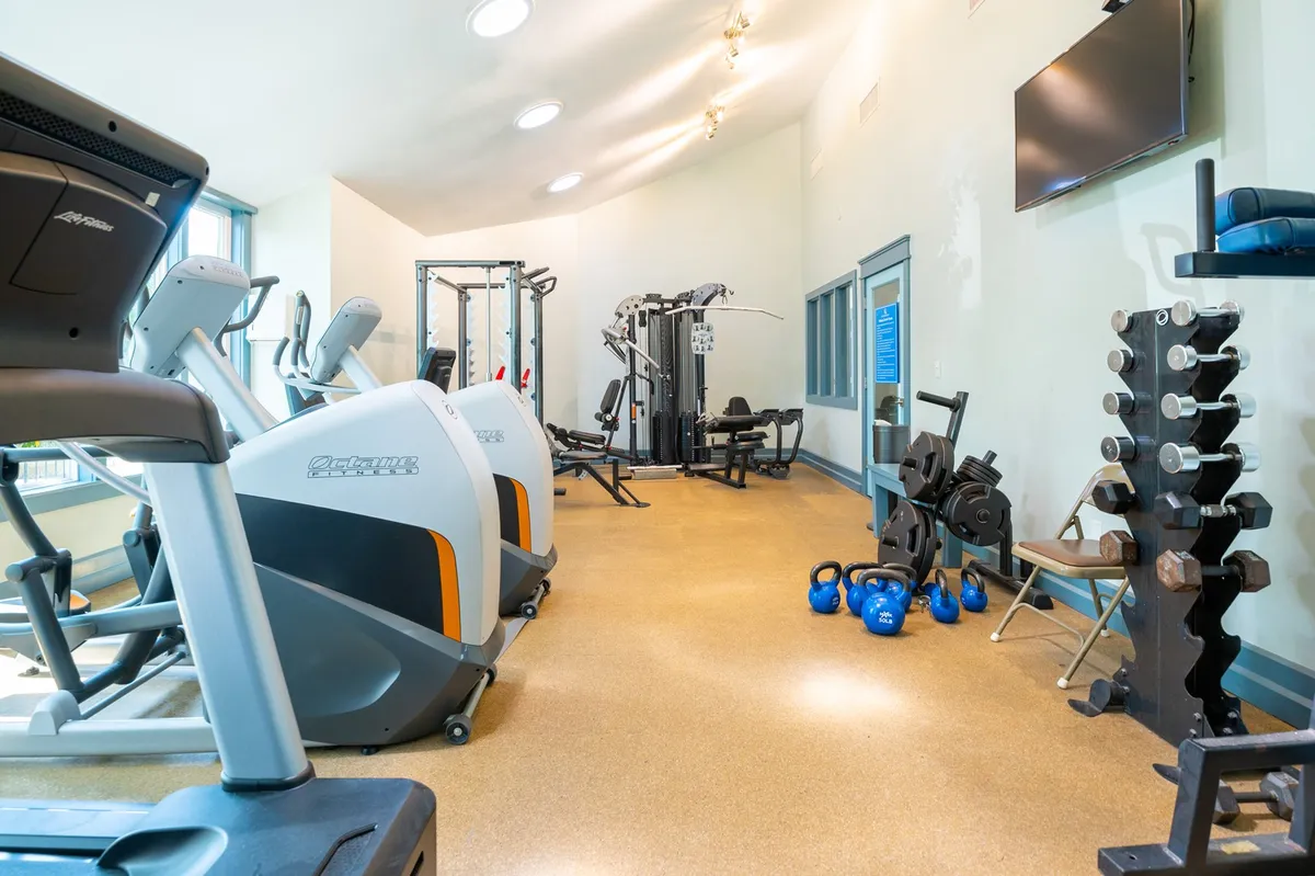 A modern fitness center equipped with treadmills, ellipticals, weight machines, and kettlebells. The space is bright and active, inviting guests to stay fit with a variety of exercise options.